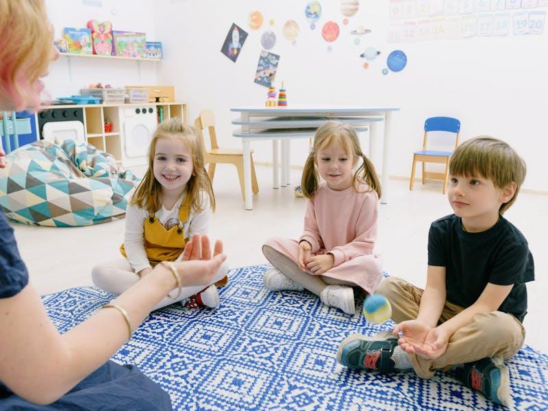 Kinder spielen gemeinsam mit Erzieherin in einer modernen Kita